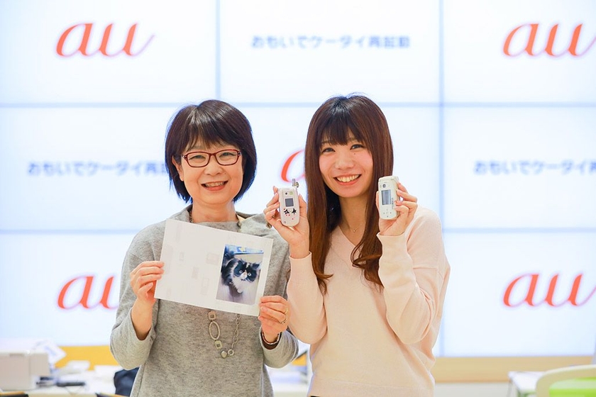 再起動したケータイからお気に入りの１枚をプリントアウトして微笑む母娘