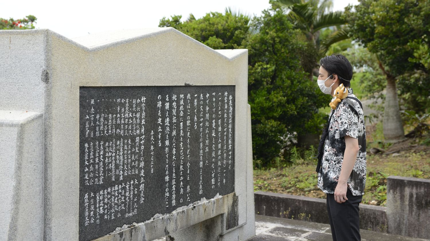 KDDIの高精度GNSS測位を活用した自動音声ガイドを装着しながら沖縄県 西表島 大富地区の街巡りツアーを楽しむ人