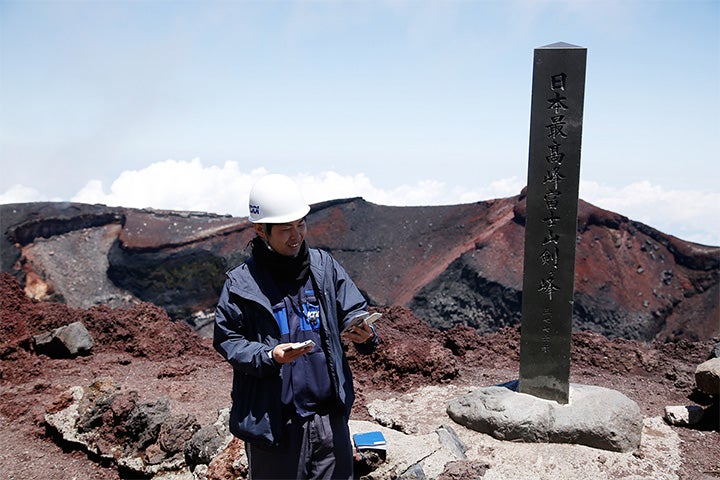実質上の日本最高地点（3,776m）である剣ヶ峰にて。もちろんスマートフォンをいじって遊んでいるわけではない。電波状況を計測中だ